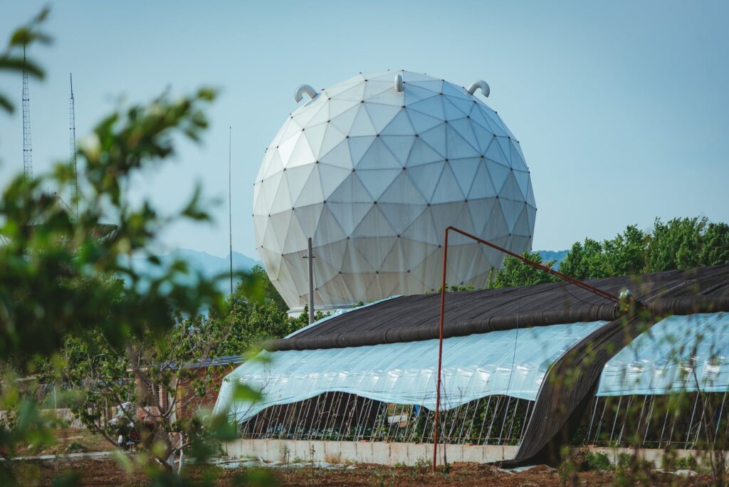 globe shaped building near greenhouses. Photo by SONIC